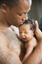 Tattooed father holding newborn baby