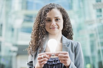 Caucasian businesswoman holding glowing light bulb