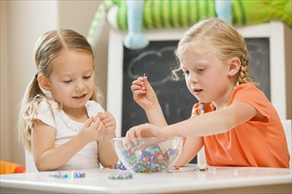 Caucasian sisters playing with beads
