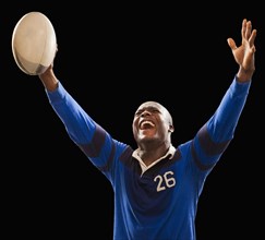 African American athlete holding rugby ball