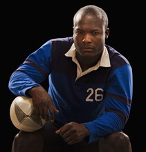 African American athlete holding rugby ball