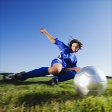 Caucasian woman kicking soccer ball