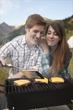 Caucasian couple cooking hamburgers on grill