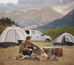 Caucasian man building campfire at campsite