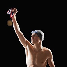 Caucasian teenage boy in swim cap and goggles holding medal