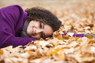 Caucasian woman laying in autumn leaves