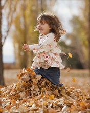 Caucasian girl playing in autumn leaves