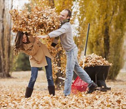 Caucasian couple raking autumn leaves
