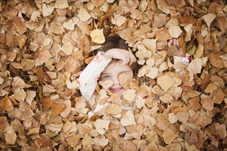 Caucasian girl laying in autumn leaves