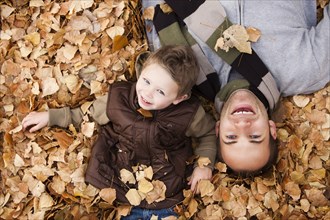 Caucasian father and son laying in autumn leaves