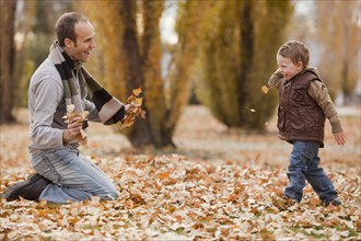 Caucasian father and son playing in autumn leaves