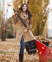 Caucasian woman raking autumn leaves