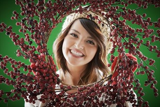 Mixed race woman holding berry wreath