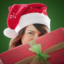 Mixed race woman in Santa hat holding Christmas gift