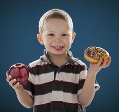 Caucasian boy holding apple and donut