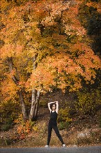 Caucasian woman stretching in autumn road