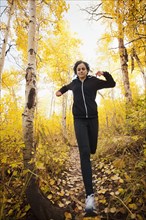 Caucasian woman running in autumn forest