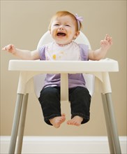Caucasian baby girl crying in high chair
