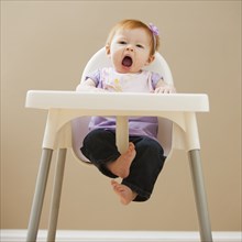 Caucasian baby girl yawning in high chair