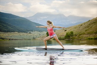 Caucasian woman practicing yoga on paddle board
