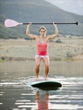 Caucasian woman practicing yoga on paddle board