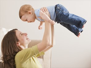 Caucasian mother lifting son in the air