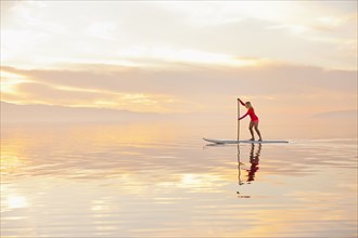 Caucasian woman standing on paddle board