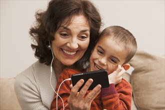 Caucasian grandmother and grandson listening to mp3 player