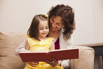 Caucasian grandmother reading book to granddaughter