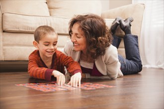 Caucasian grandmother and granddaughter playing cards on floor