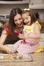 Caucasian mother and daughter baking cookies