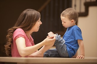 Caucasian mother putting bandage on son's knee
