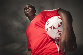 Black soccer player holding ball