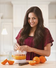 Mixed race woman making fresh orange juice