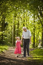 Caucasian grandfather and granddaughter walking in woods