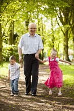 Caucasian grandfather and grandchildren walking in woods