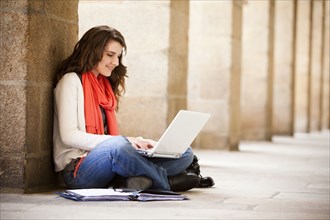 Caucasian woman sitting on ground with laptop