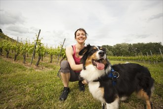 Caucasian woman petting dog in vineyard
