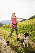 Caucasian woman with dog stretching in vineyard