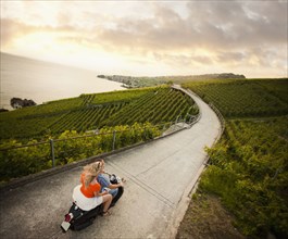 Couple riding scooter in vineyard