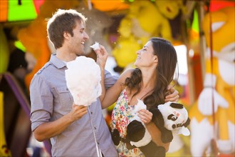 Caucasian couple sharing cotton candy at carnival