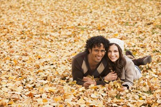 Couple laying in autumn leaves