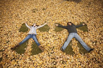 Couple making angel in autumn leaves
