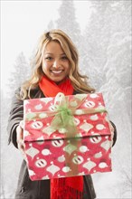Mixed race woman offering present in snow