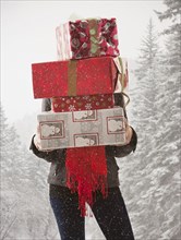 Mixed race woman holding stack of presents in snow