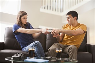 Couple arguing over remote on sofa