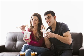 Couple eating Chinese food on sofa