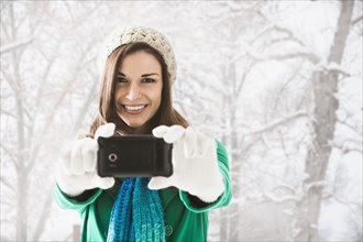 Caucasian woman taking pictures in snow