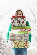 Caucasian woman holding Christmas gifts in snow