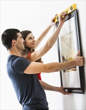 Couple measuring picture frame on wall